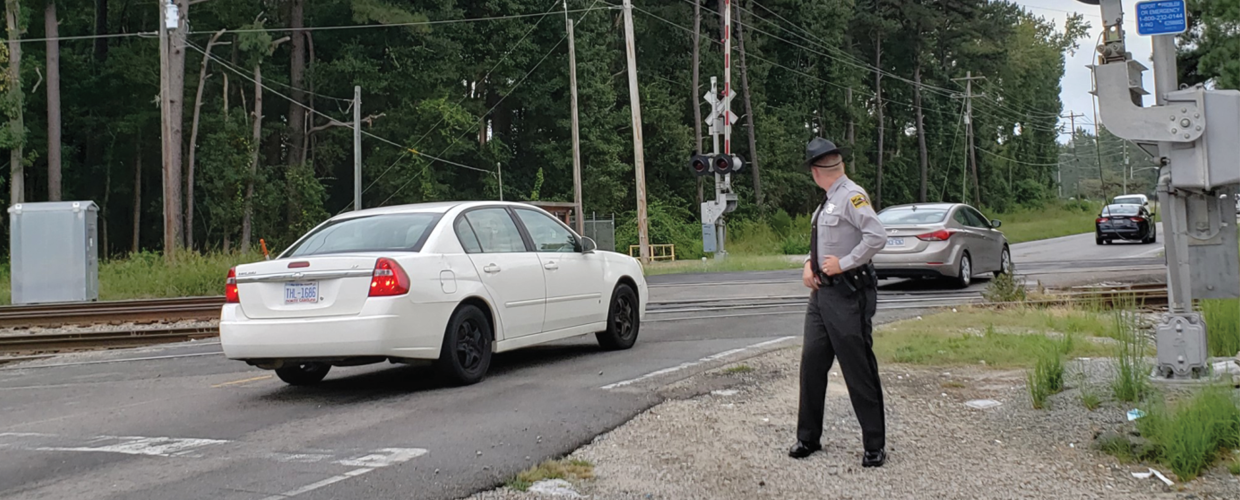 A state trooper helping vehicles navigate at a railroad crossing